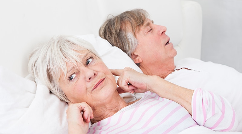 Senior woman annoyed by husbands snoring