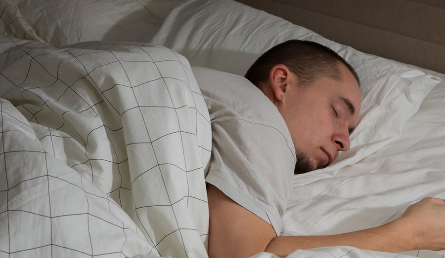 Man sleeping in bed and holding a mobile phone