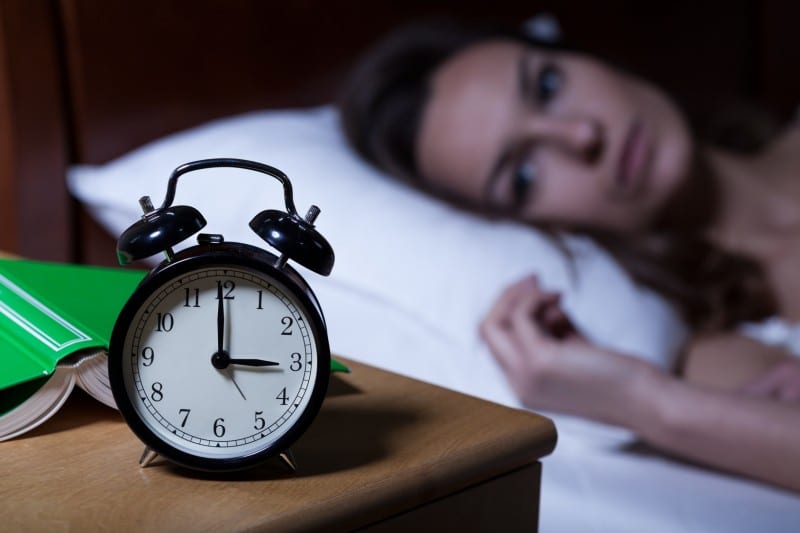 woman lays in her bed, wide awake in the middle of the night