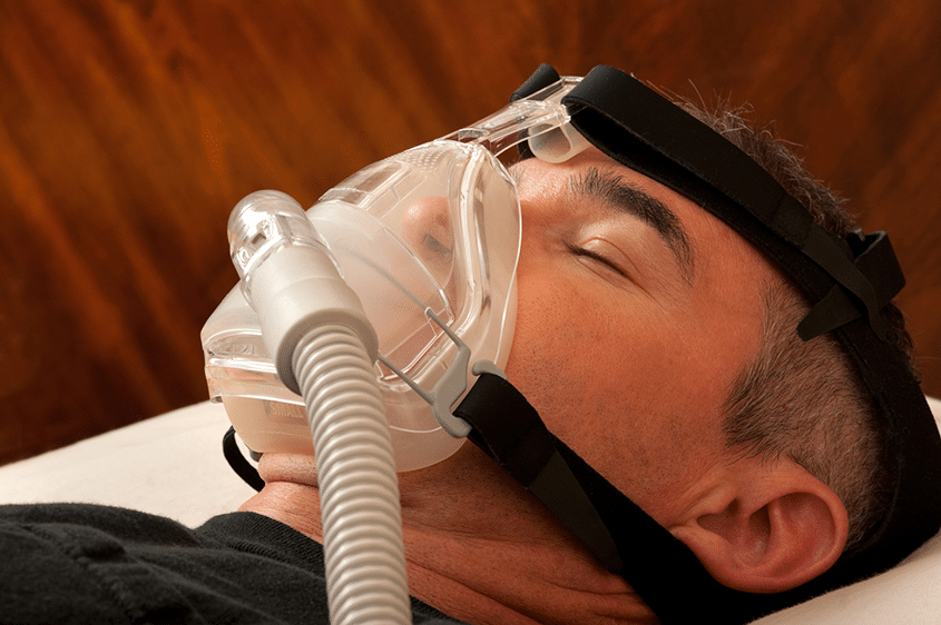 man sleeping on his back with CPAP mask on