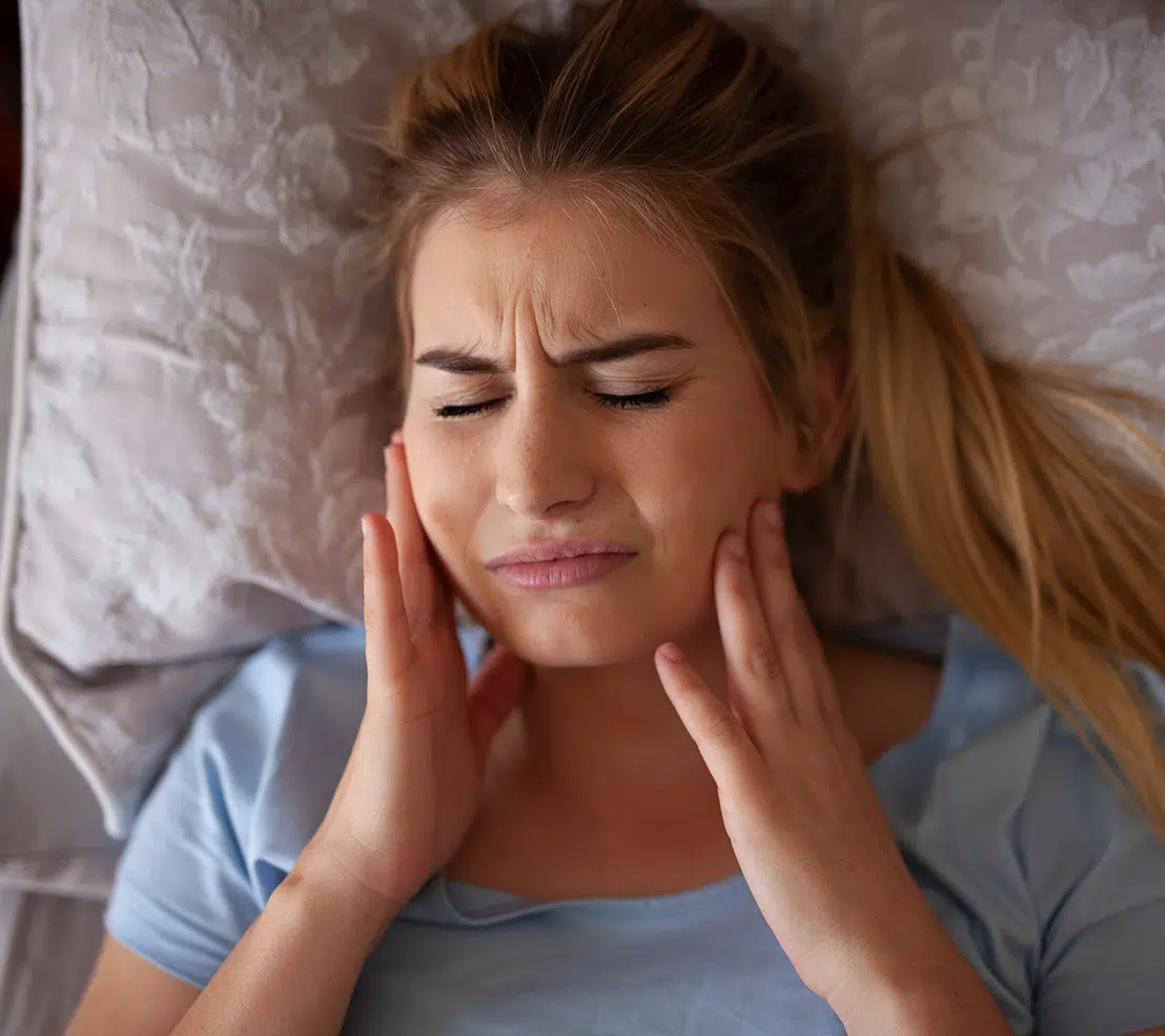Woman lying in bed with jaw pain